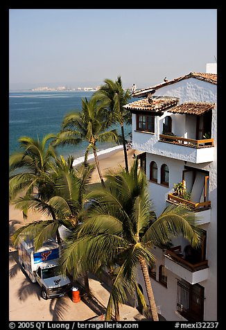 White adobe building with red tile roof,  palm trees and ocean, Puerto Vallarta, Jalisco. Jalisco, Mexico