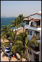 White adobe building with red tile roof,  palm trees and ocean, Puerto Vallarta, Jalisco. Jalisco, Mexico