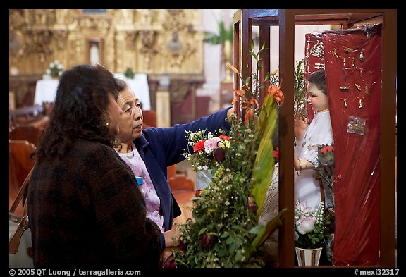 Women placing flowers in front of a Saint figure. Zacatecas, Mexico