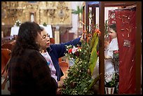 Women placing flowers in front of a Saint figure. Zacatecas, Mexico (color)