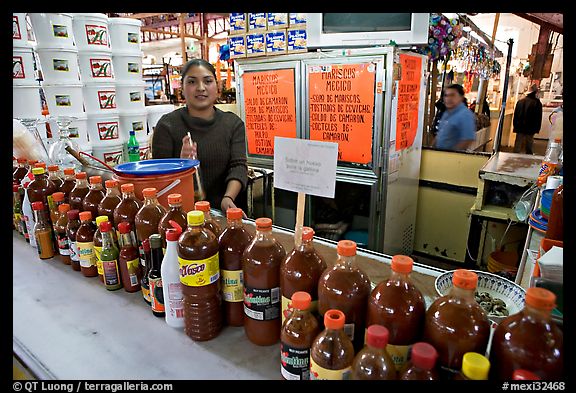 Woman at a booth with lots of chili bottles in Mercado Hidalgo. Guanajuato, Mexico