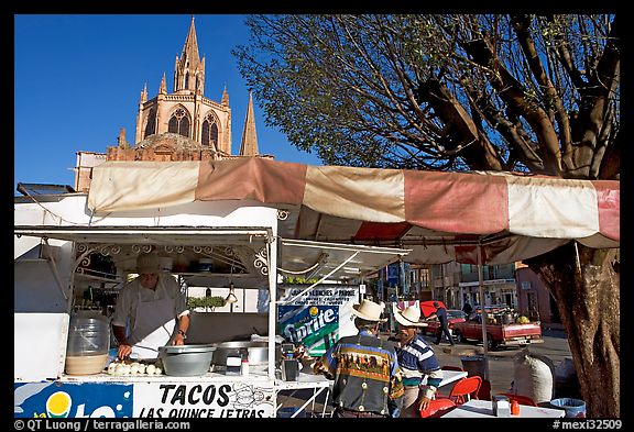 Taco stand on town plaza with cathedral in background. Mexico