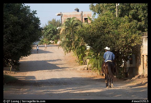 Man on horse going down a village street. Mexico