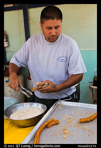 Man coating churros in sugar. Baja California, Mexico