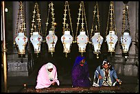 Women worshiping beneath hanging lamps inside the Church of the Holy Sepulchre. Jerusalem, Israel