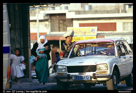 Women next to an old French Peugeot car, Hebron. West Bank, Occupied Territories (Israel) (color)