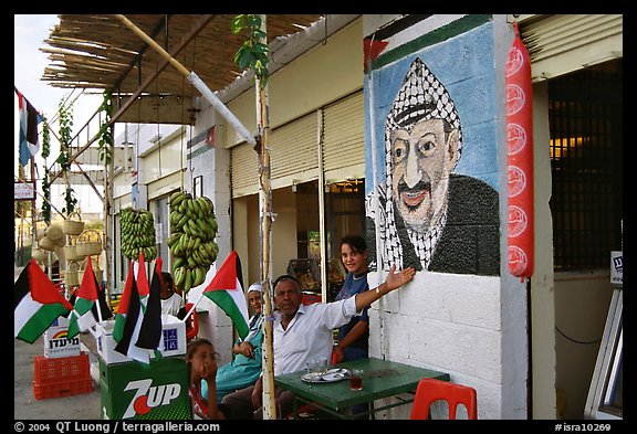 Palestinian cafe owner pointing proudly to a painting of Yasser Arafat, Jericho. West Bank, Occupied Territories (Israel)