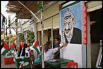 Palestinian cafe owner pointing proudly to a painting of Yasser Arafat, Jericho. West Bank, Occupied Territories (Israel) (color)