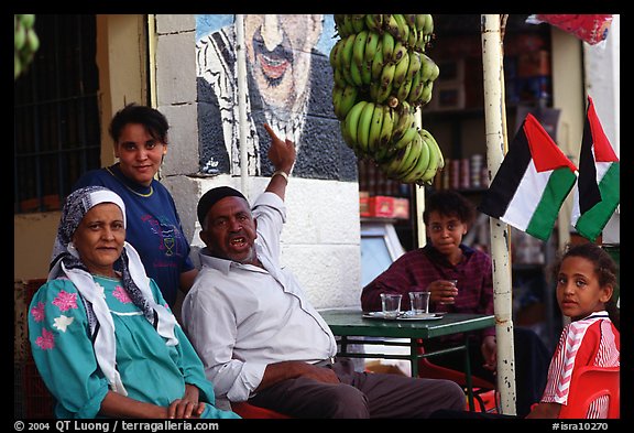 Palestinian head of family  pointing  to a mural of Yasser Arafat, Jericho. West Bank, Occupied Territories (Israel) (color)