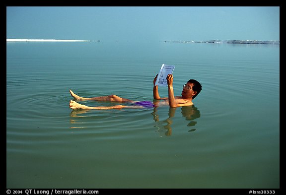 Visitor reading while floating in the Dead Sea. Israel