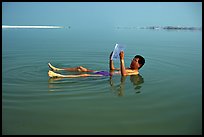 Visitor reading while floating in the Dead Sea. Israel (color)