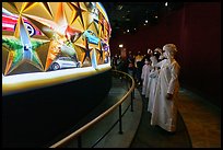 Visitors in Arab dress looking at curved wall of stars with projected media, USA Pavilion. Expo 2020, Dubai, United Arab Emirates ( color)