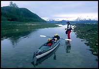 Kayaker tows kayak into a shallow tidal channel into Scidmore Bay. Glacier Bay National Park, Alaska