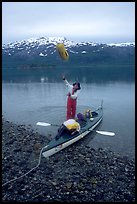 Kayaker unloading the kayak by throwing stuff sacks out. Glacier Bay National Park, Alaska