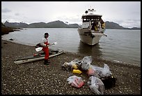Kayaker standing with gear wrapped in plastic bags after drop-off. Glacier Bay National Park, Alaska ( color)