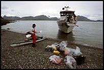 Kayaker standing with gear wrapped in plastic bags after drop-off. Glacier Bay National Park, Alaska