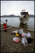 Kayaker standing with gear wrapped in plastic bags after drop-off. Glacier Bay National Park, Alaska (color)