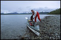 Kayaker loading gear into a double kayak. Glacier Bay National Park, Alaska