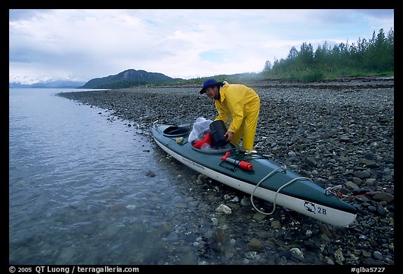 Kayaker unloading gear from a double kayak. Glacier Bay National Park, Alaska (color)