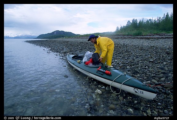 Kayaker unloading gear from a double kayak. Glacier Bay National Park, Alaska