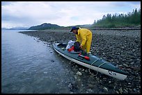Kayaker unloading gear from a double kayak. Glacier Bay National Park, Alaska ( color)