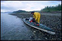 Kayaker unloading gear from a double kayak. Glacier Bay National Park, Alaska (color)