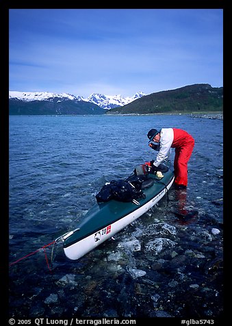 Kayaker tying up gear on top of the kayak,  East Arm. Glacier Bay National Park, Alaska