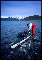 Kayaker tying up gear on top of the kayak,  East Arm. Glacier Bay National Park, Alaska