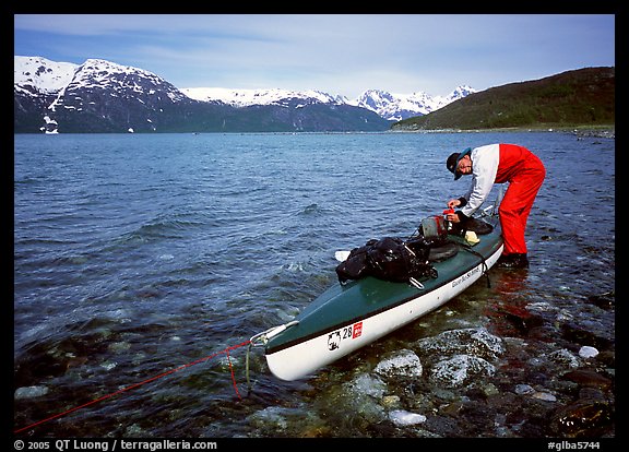 Kayaker tying up gear on top of the kayak,  East Arm. Glacier Bay National Park, Alaska (color)