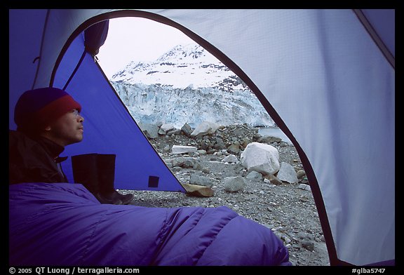 Camper lying in sleeping bag looks at Lamplugh Glacier. Glacier Bay National Park, Alaska