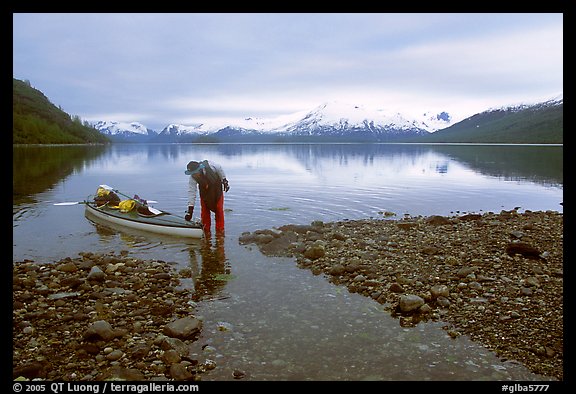 Kayaker standing in Scidmore Bay next to a shallow tidal channel. Glacier Bay National Park, Alaska