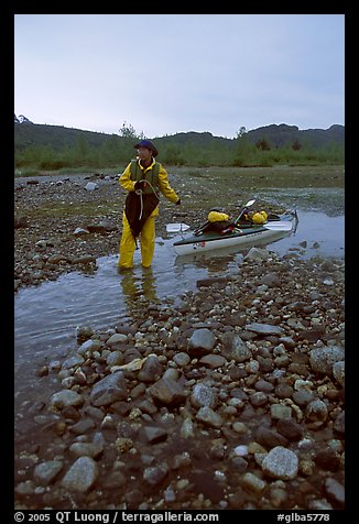 Kayaker towing the kayak in the narrowest part of a tidal channel into Scidmore Bay. Glacier Bay National Park, Alaska (color)