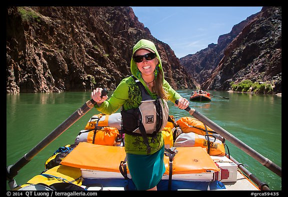 Woman standing on raft to paddle raft with oars. Grand Canyon National Park, Arizona (color)