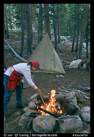 Woman preparing food at campfire, Le Conte Canyon. Kings Canyon National Park, California