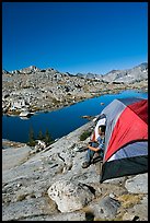 Man looking out from tent above lake, morning, Dusy Basin. Kings Canyon National Park, California