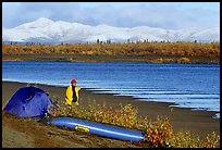 Canoeist standing next to tent and canoe with snowy mountains in the background. Kobuk Valley National Park, Alaska ( color)