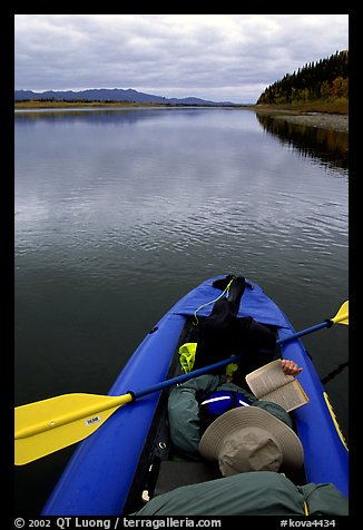 Canoeist reading a book while floating downriver. Kobuk Valley National Park, Alaska