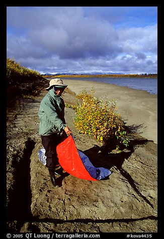 Camper folding the tarp while breaking camp. Kobuk Valley National Park, Alaska (color)