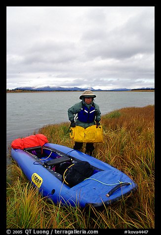 Canoeist unloading the canoe on a grassy riverbank. Kobuk Valley National Park, Alaska