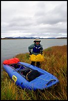 Canoeist unloading the canoe on a grassy riverbank. Kobuk Valley National Park, Alaska (color)