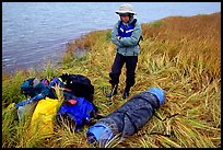 Canoeist standing next to gear and deflated and folded  canoe. Kobuk Valley National Park, Alaska