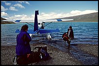 Pilot unloading a backpack from the floatplane on Lake Turquoise. Lake Clark National Park, Alaska (color)