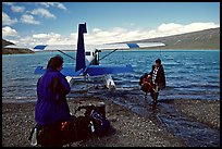 Pilot unloading a backpack from the floatplane on Lake Turquoise. Lake Clark National Park, Alaska