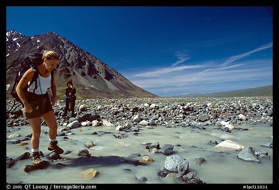 Hiker crossing a stream next to Lake Turquoise. Lake Clark National Park, Alaska (color)