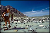 Hiker crossing a stream next to Lake Turquoise. Lake Clark National Park, Alaska