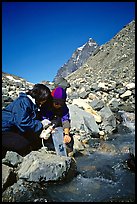 Hikers filing up a water container with a filter. Lake Clark National Park, Alaska