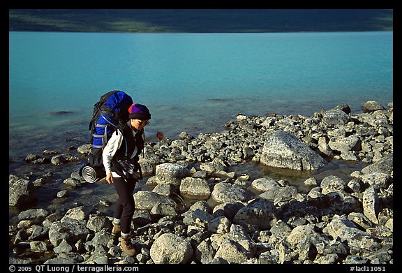 Backpacker walking on rocks on the shore of Turquoise Lake. Lake Clark National Park, Alaska (color)