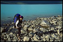 Backpacker walking on rocks on the shore of Turquoise Lake. Lake Clark National Park, Alaska (color)