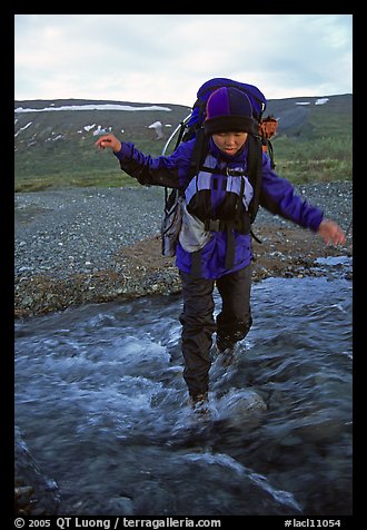 Backpacker balancing herself while crossing a stream. Lake Clark National Park, Alaska (color)