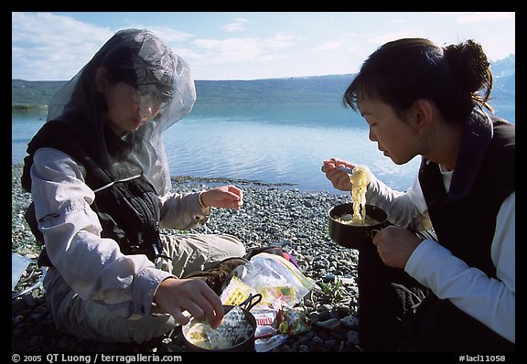 Backpackers eating noodles from a camp pot. Lake Clark National Park, Alaska (color)